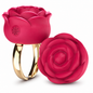 A rose-shaped ring with a glossy deep pink bloom and a polished gold band, shown alongside a matching detached rose-shaped component on a white background.